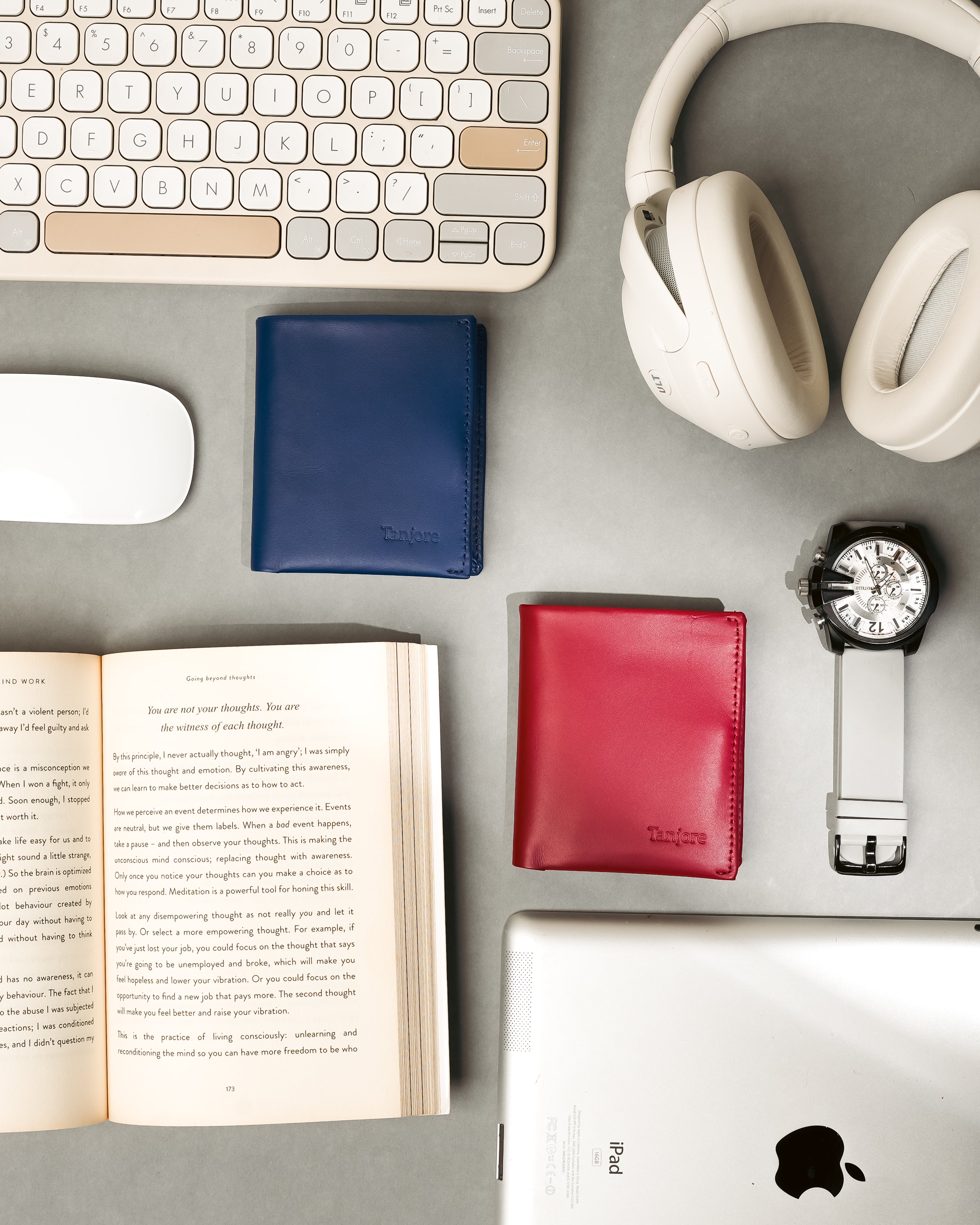 A creative desk setup with Tanjore Reserve Sleeves in Navy and Plum, surrounded by headphones, an iPad, and a book. Functional RFID wallets for daily organization.
