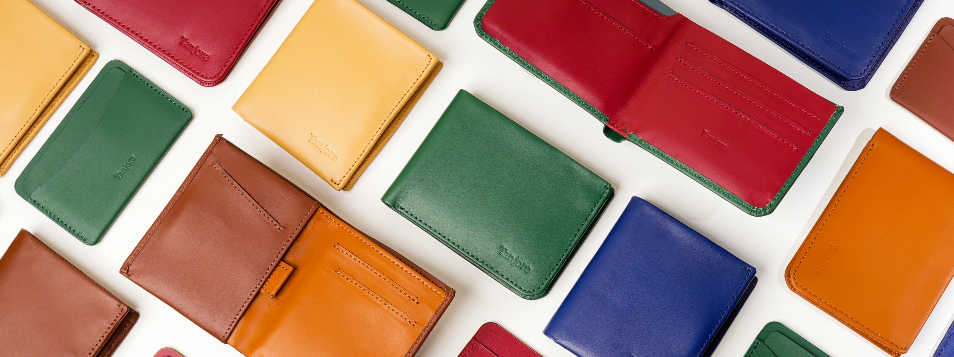 Wide banner image displaying the variety of Tanjore leather goods. Features the Modern Classic 2.0 bifold and Reserve Sleeve with Pull Tab, showcasing the premium texture of Full Grain Nappa Leather.